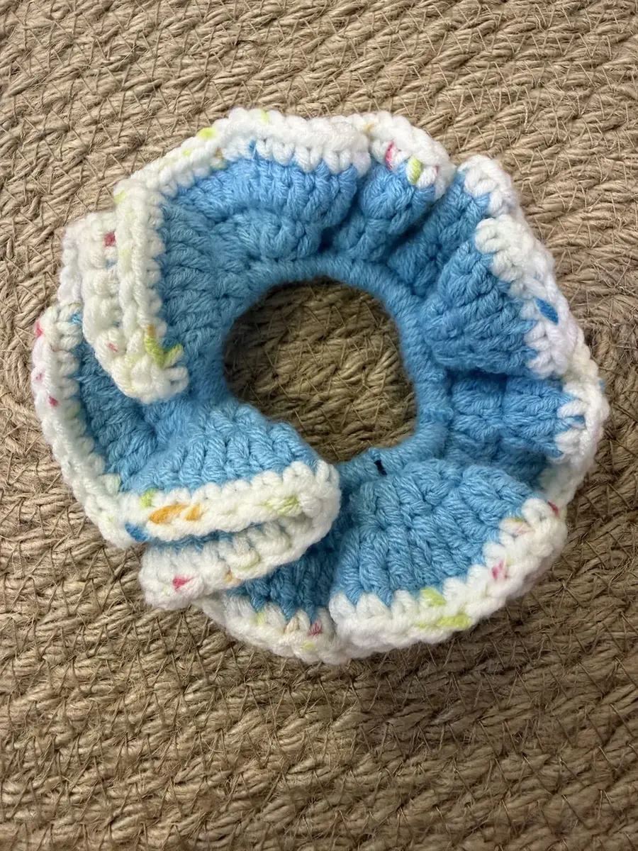 A handmade ruffle scrunchie in sky blue with a white confetti edge.