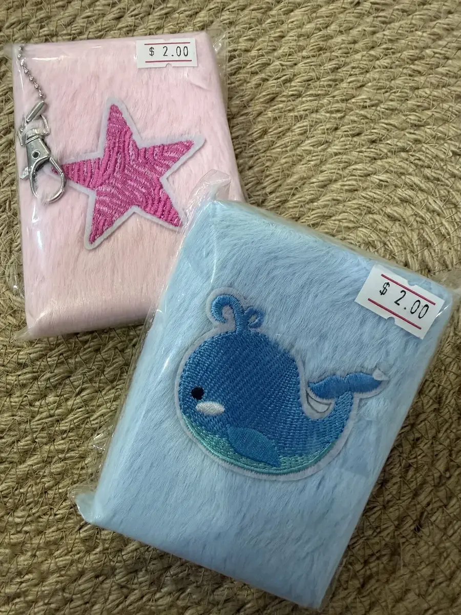 Two fluffy mini notebooks, one pink with a star and one blue with a whale.