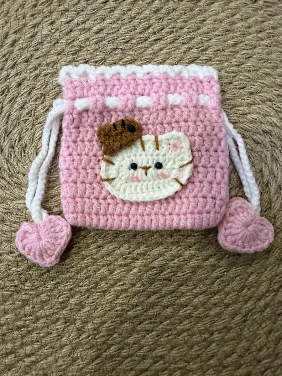 A pink cat drawstring pouch with heart tassels.