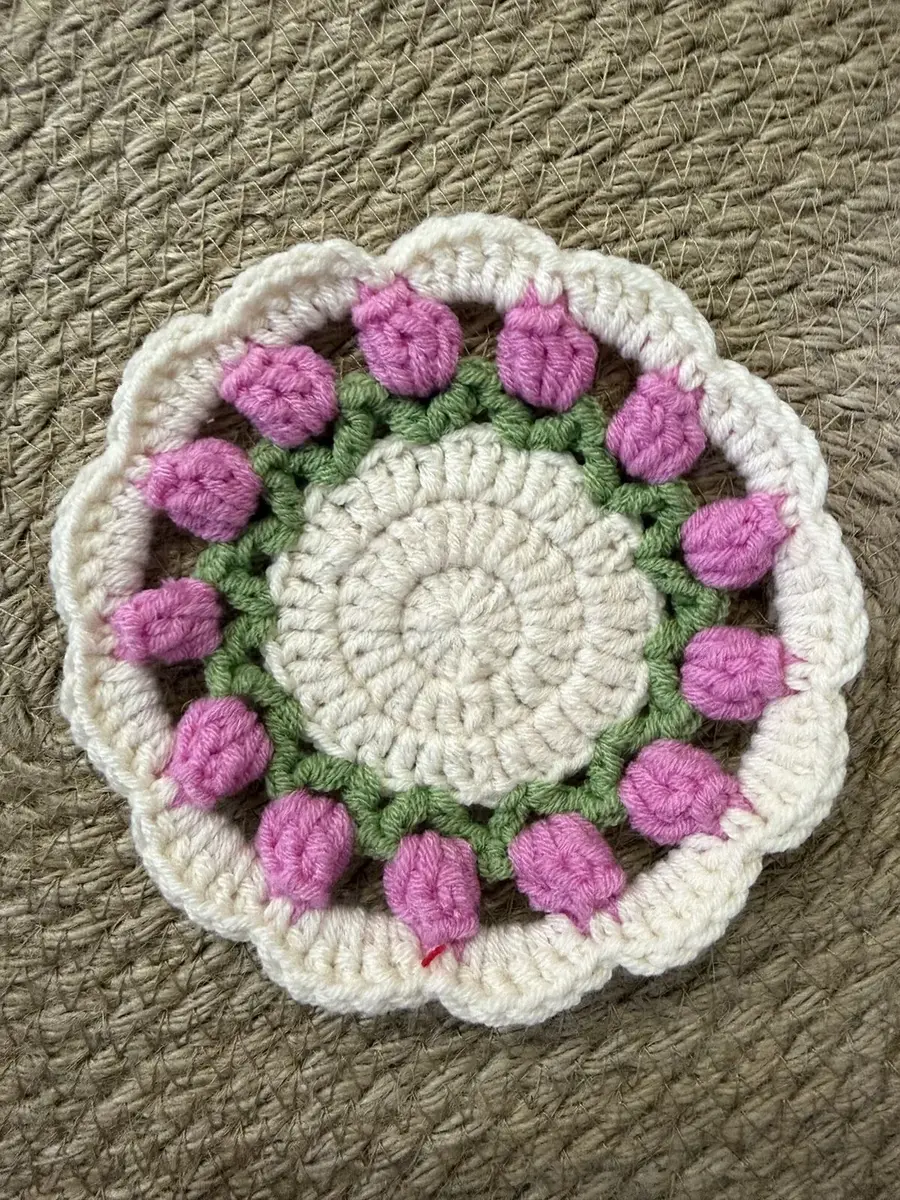 A flower coaster with bright pink puffs.