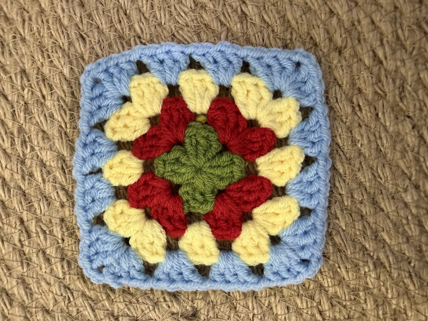 A crochet granny square in red, yellow and green.